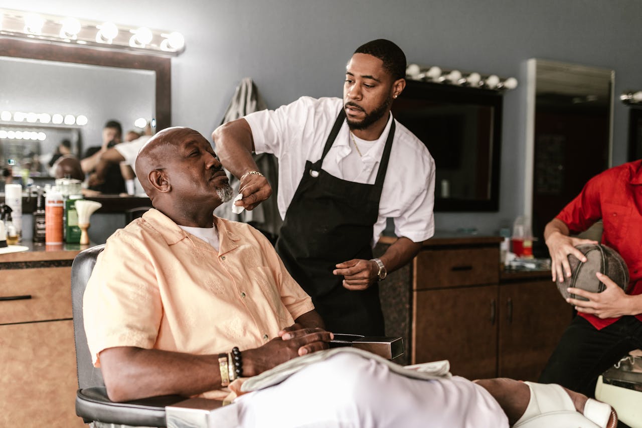 Barber working on a clients haircut in a modern barbershop. Candid indoor scene.