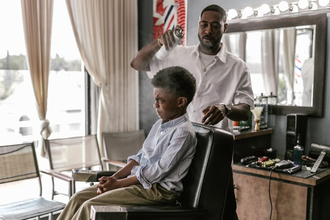 A barber styles a young boys hair with precision in a modern salon setting.